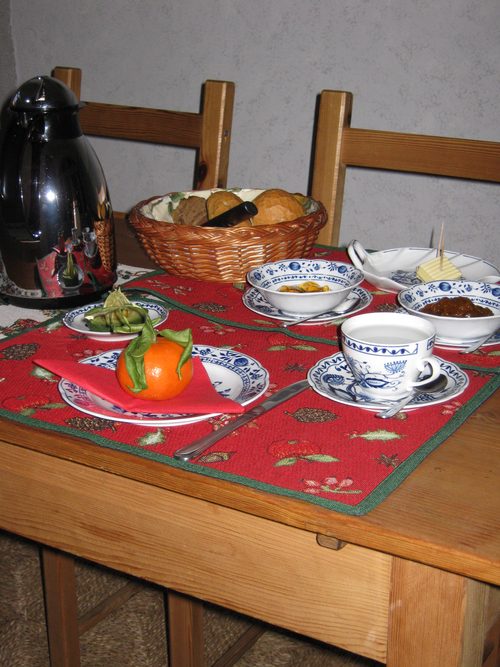 Liebevoll gedeckter Frühstückstisch mit Brötchenkorb und Konfitüre