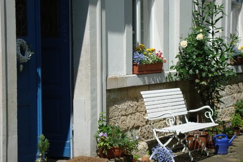 Weiße Gartenbank zwischen Blumen und Rosen